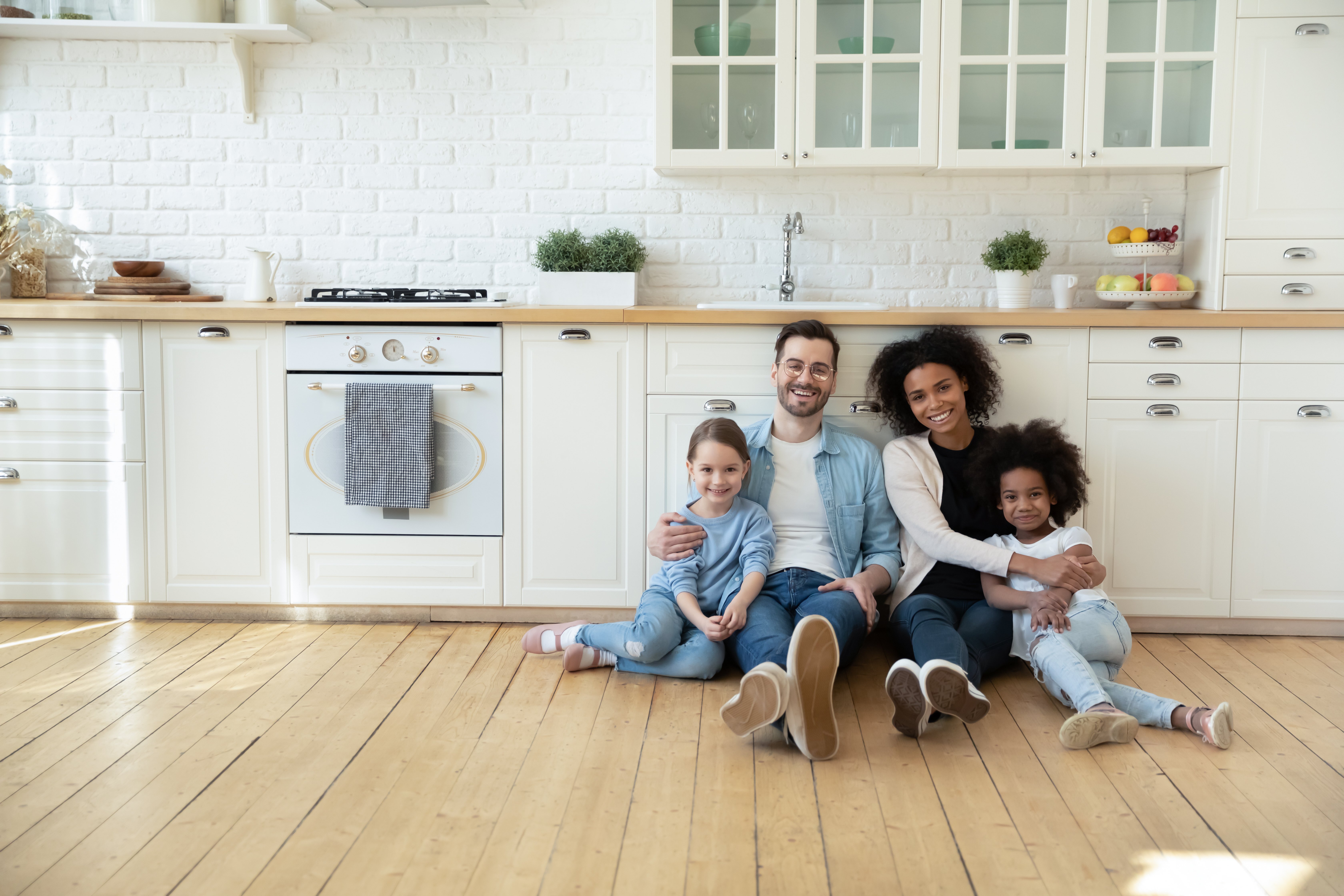 diverse family sitting on floor of kitchen