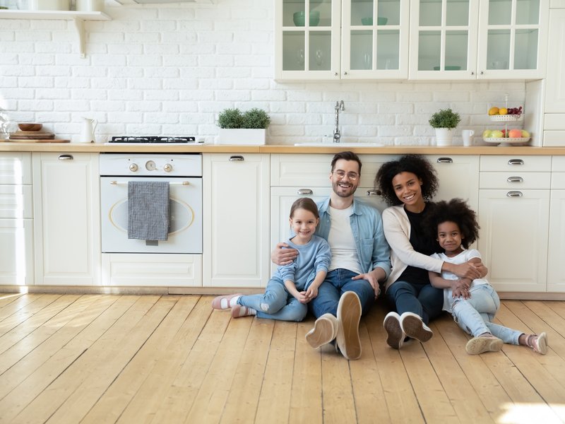 diverse family sitting on floor of kitchen